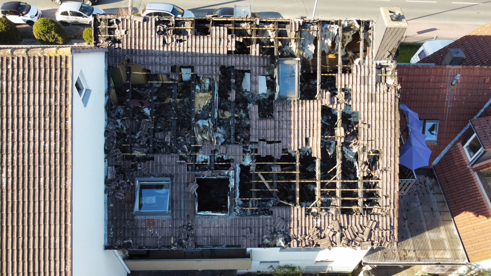 Luftaufnahme eines Dachs mit schweren Brandschäden, abgebrannten Ziegeln und offener Dachkonstruktion