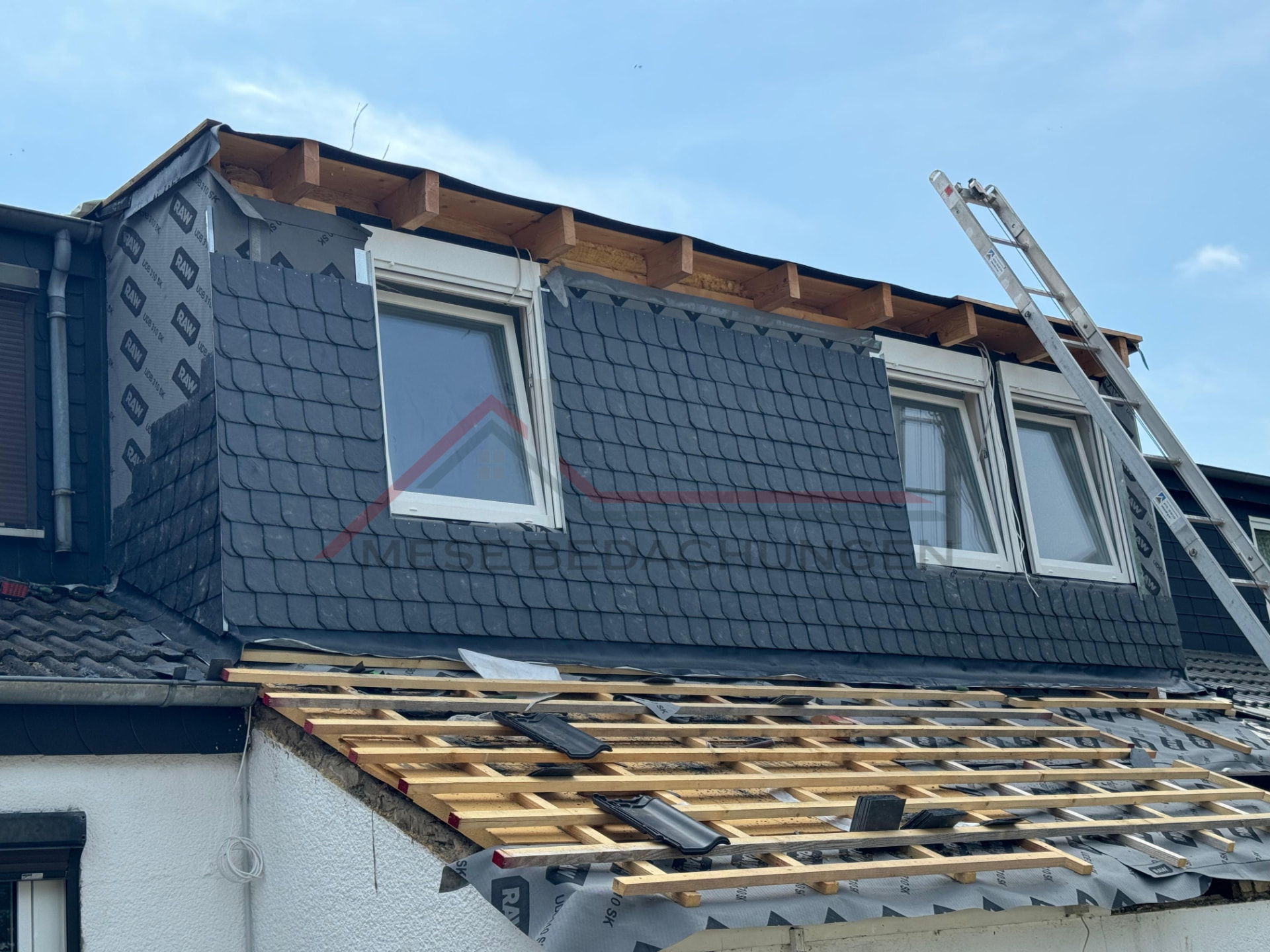 Dachgaube mit dunkelgrauer Schieferverkleidung, frisch gedeckte Dachlatten und Fenster